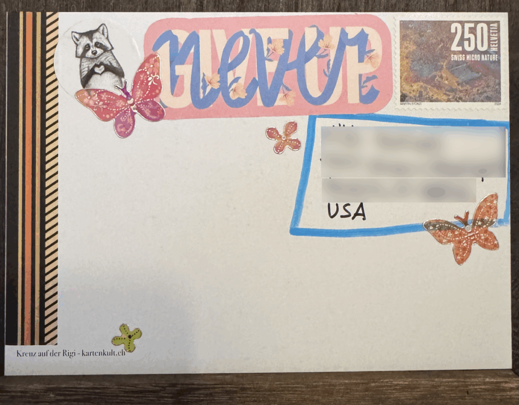Rückseite einer verzierten Postkarte mit Stickern und der Aufschrift "Never Give Up"