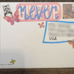 Rückseite einer verzierten Postkarte mit Stickern und der Aufschrift "Never Give Up"